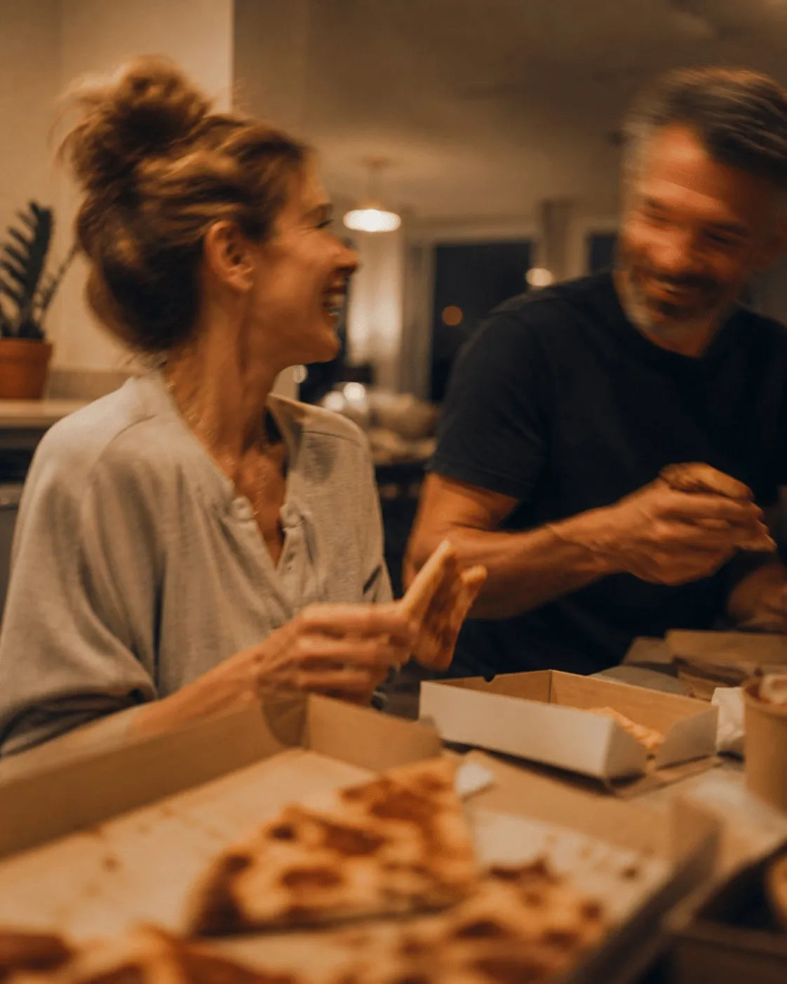 Frau lacht mit Freunden beim Pizzaessen